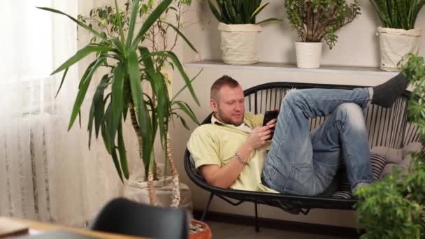 男人使用手机 浏览智能手机应用 看屏幕 躺在自家花园沙发上的网店购物 恋童癖设计 — 图库视频影像