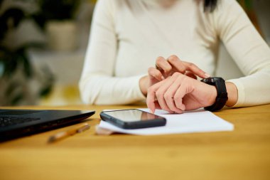 Tanımlanamayan bir kadın akıllı bant kullanıyor, kadın bileğinde akıllı saati olan serbest çalışan bir kadın, cihazda dokunmatik ekran kullanıyor.