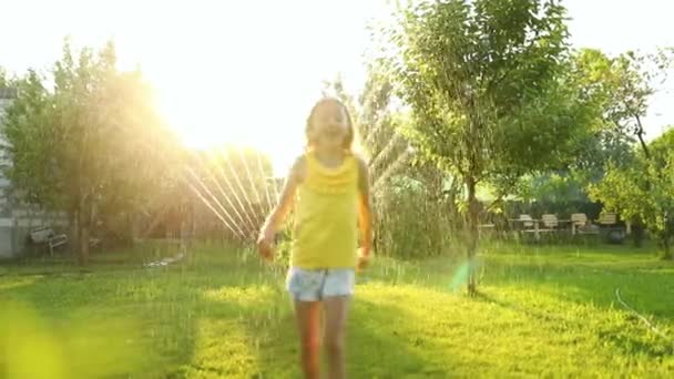 幸せな子供の女の子は庭のスプリンクラーを実行してジャンプし 夏の屋外の水遊び裏庭で自宅で 晴れた日にスプラッシュ — ストック動画