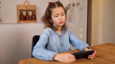 Evde cep telefonuyla oyun oynayan üzgün kız, akıllı telefon kullanan çocuk, akıllı telefon bağımlısı, duygusal kız..