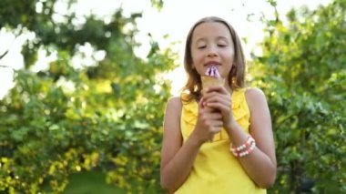 Cute girl with braces eating italian ice cream cone smiling while resting in park on summer day, child enjoying ice cream outdoor, happy holidays, summertime