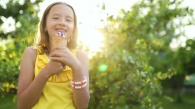 Cute girl with braces eating italian ice cream cone smiling while resting in park on summer day, child enjoying ice cream outdoor, happy holidays, summertime