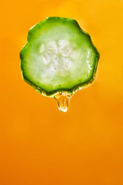 Gel, juice drips from cucumber slices with gel on yellow background, natural medicinal plant for organic cosmetics, alternative medicine, health and beauty spa concept, drop of cucumber.