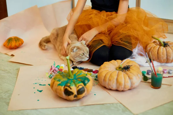 快乐的小女孩在家里用猫装饰南瓜 小女孩在橙色万圣节前夕用南瓜画着脸 假日装饰概念 — 图库照片