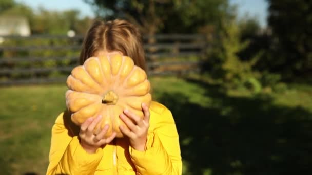 Happy Child Girl Covers Face Pumpkin Outdoors Halloween Orange Pumpkin — Vídeo de stock