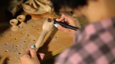 Elektrikli aletler kullanan bir kadın. Tahta çatal bıçak kaşığı, oyma makinesi, öğütme makinesi, el yapımı eşyalar, atölyede bir kadın..