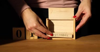 Woman hand change, sets the date on the wooden calendar on 01 September , Back to School, hard light, sunlight,