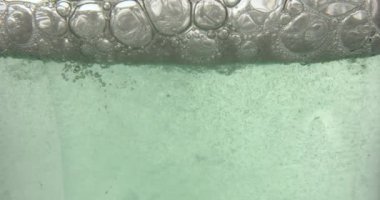 Close up of blue bubble serum poured in a medical glass bottle, background, natural essential oil, cosmetic, medicine.