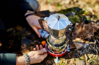 Man brewing coffee from a geyser coffee maker on a gas burner,, autumn outdoor. Male prepares coffee outdoors, travel activity for relaxing, bushcraft, adventure, travel, tourism and camping concept
