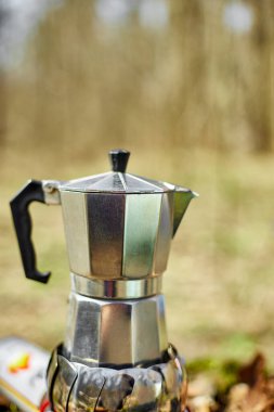Making camping coffee from a geyser coffee maker on a gas burner,, autumn outdoor. Male prepares coffee outdoors, travel activity for relaxing, bushcraft, adventure, travel, tourism and camping concept