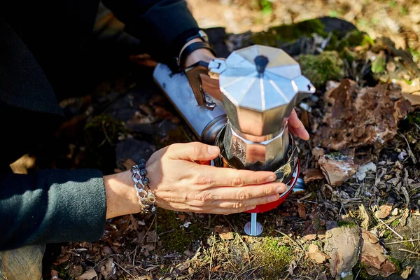 Man brewing coffee from a geyser coffee maker on a gas burner,, autumn outdoor. Male prepares coffee outdoors, travel activity for relaxing, bushcraft, adventure, travel, tourism and camping concept