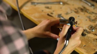 Çalışan bir kadın öğütücü kullanıyor, kadın eli metal bir fındık öğütüyor, atölyede cıvatalar, metal işçiliğinde kıvılcımlar...