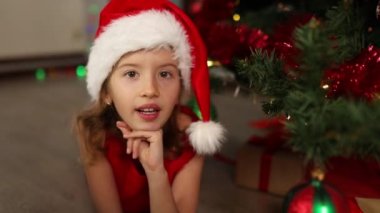 Noel Baba şapkalı kız yalan söylüyor, Noel ağacının yanında şarkı söylüyor. Mutlu Noeller ve mutlu tatiller.