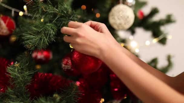 孩子们把装饰玩具球挂在圣诞树上的枝条上 挂在山核桃的背景上 新年的概念 圣诞快乐及节日快乐 — 图库视频影像