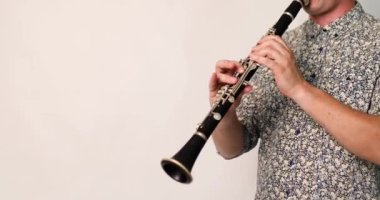 Beyaz arka planda klasik rüzgar enstrümanı klarneti çalan müzisyen şarkı ve müzikle rahatlıyor. Tek kamışlı ahşap rüzgar enstrümanı çalma alıştırması yapıyorum.