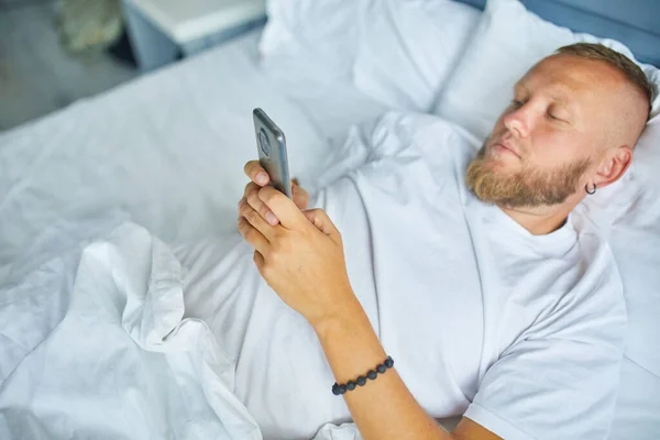 Skäggig Man Med Hjälp Smartphone Morgonen Mysiga Medan Liggande Sängen — Stockfoto