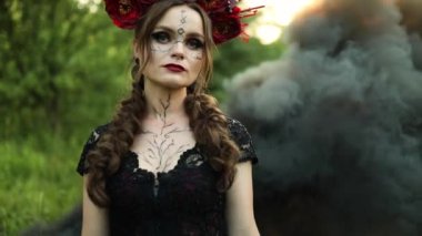 Uzun siyah elbiseli güzel cadı çiçek çemberi, dışarıda siyah duman, Santa Muerte karnavalı Cadılar Bayramı, Azizler Günü, Cadılar Bayramı korkunç konsepti,