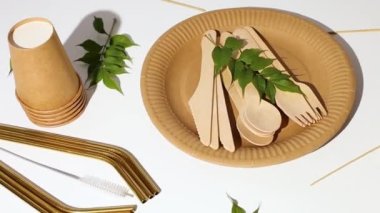 Çevre dostu sofra takımı, yeniden kullanılabilir tek kullanımlık tabaklar, fincanlar, paslanmaz çelik pipetler ve beyaz arka planda sert gölgeli temizlik fırçası.