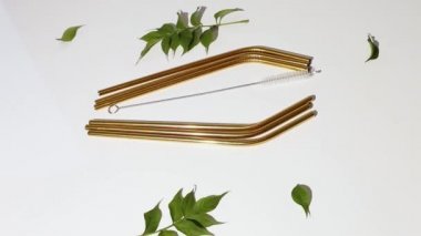 Dönüşümlü çevre dostu yeniden kullanılabilir paslanmaz çelik pipetler ve beyaz arka planda sert ışıklı fırça, üst görünüm.