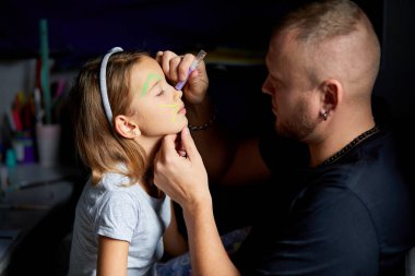 Kız ve baba bir yüz çiziyor, eğleniyor, evde birlikte kanepede vakit geçiriyorlar, karanlık ışık, babalar günü, aile yaratıcılığı aktiviteleri..