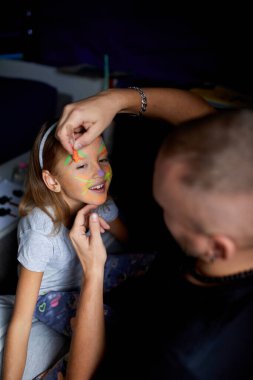 Kız ve baba bir yüz çiziyor, eğleniyor, evde birlikte kanepede vakit geçiriyorlar, karanlık ışık, babalar günü, aile yaratıcılığı aktiviteleri..