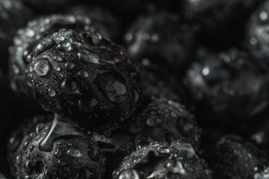 Olgun tatlı yaban mersinine su damlası. Metnin için fotokopi alanı olan taze yabanmersini arkaplanı. Vejetaryen ve vejetaryen kavramı. Yaban mersinli böğürtlenlerin makro dokusu. Yaban mersinli dokular kapanıyor.