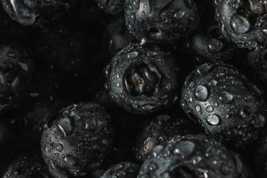 Olgun tatlı yaban mersinine su damlası. Metnin için fotokopi alanı olan taze yabanmersini arkaplanı. Vejetaryen ve vejetaryen kavramı. Yaban mersinli böğürtlenlerin makro dokusu. Yaban mersinli dokular kapanıyor.