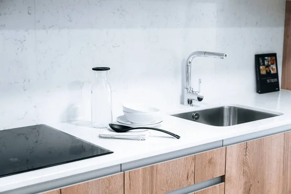 Lavabosu, seramik hobisi, mermer tezgahı ve arka kitabı olan minimalist ve parlak bir mutfak.