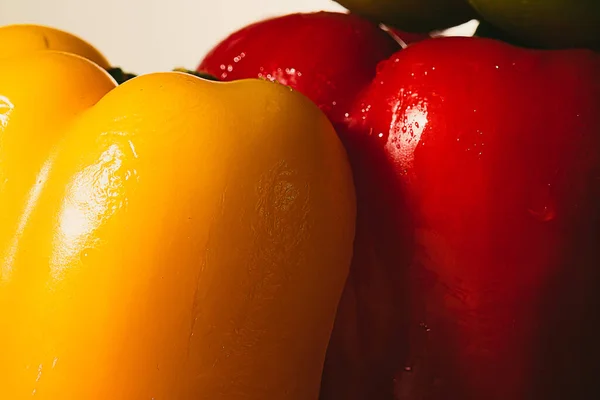 details of the skin of wet bell pepper slices in red and yellow on a white background