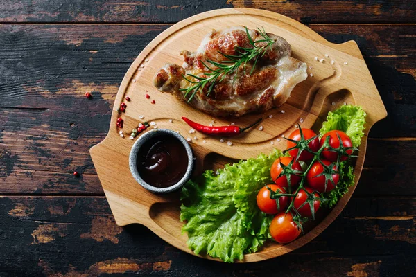 Steak de porc sur une planche de bois avec tomates cerises et salade. Nourriture rustique — Photo