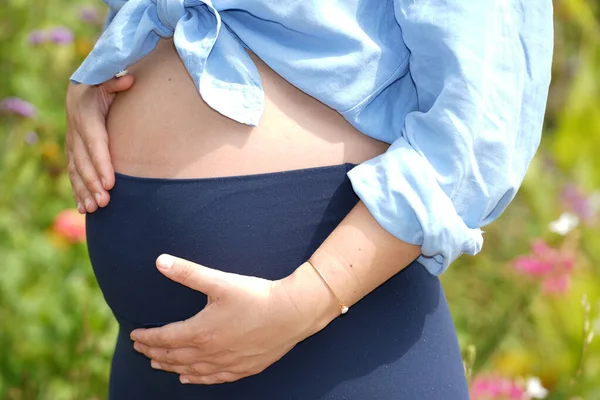 お腹を抱いた公園で妊娠30代40代の女性 — ストック写真