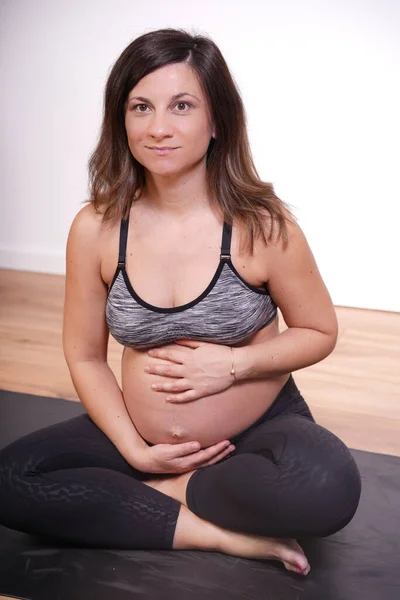 40成熟した妊娠中の大人で運動服ヨガマットの上に座って運動を行う — ストック写真
