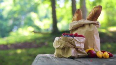 Fruits and baguettes in paper bag during picnic in the park in sunny summer day