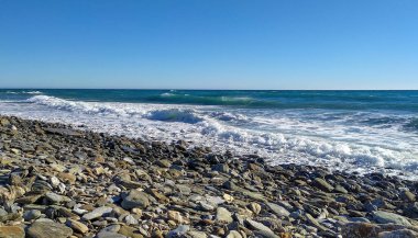 Atlantik Okyanusu 'ndaki bir sahilin ya da körfezin panorama görüntüsü. Taşlar ve dalgalarla dolu. Yazın güneşli bir günde bulutlu mavi gökyüzü.