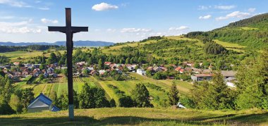 Slovakya 'nın kuzeyindeki High Tatras' ın eteklerindeki doğal manzarada bir köyün önünden geçen üç Hristiyan ahşap haç.