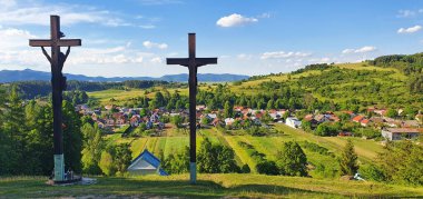 Slovakya 'nın kuzeyindeki High Tatras' ın eteklerindeki doğal manzarada bir köyün önünden geçen üç Hristiyan ahşap haç.