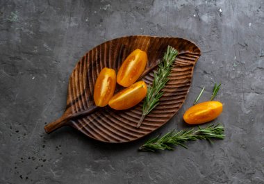 Ahşap tepside, beton bir arka planda sarı domatesler.