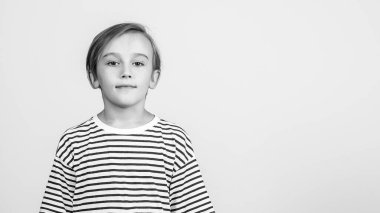 Stüdyoda poz veren çocuk. Uzayı kopyala, afiş. Çocuk kameraya bakıyor. Çocuk stili ve moda. Güzel saç stili olan sevimli bir çocuk. Mutlu çocukluk ve olumlu duygular. Yüz ifadesi.