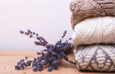 Ilık örülmüş lavantalı kıyafetler yığını. Güveden korunmak için yün kazaklar ve kurutulmuş lavanta. Kışlık kıyafetlerle dolu bir gardırop. Sonbahar, kış örgü giysileri. Sıcak yün elbiseler ördüm..