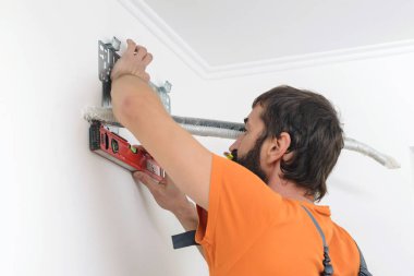 Adam yeni klima kurmaya hazırlanıyor. Kurulum sırasında modern klima. İşçi klimanın kapalı bir bölümünü kuruyor. Bakır tüpler ve plakalı radyatör.