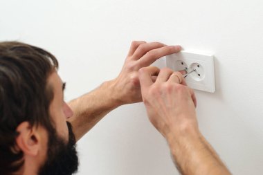 Elektrikçi yeni bir yapı kuruyor. İşçi yeni eve soket takıyor. Tadilattan sonra elektrik düğmesi takan adam. Elektrikçi beyaz duvara elektrik prizleri takıyor.