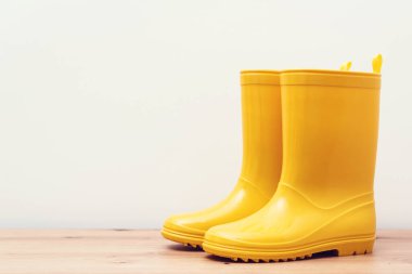 Ahşap rafta sarı çizmeler. İlkbahar ya da sonbahar yağmurlu hava için sarı yağmur botları. Sonbahar modası. Mevsimlik alışveriş ve satışlar.