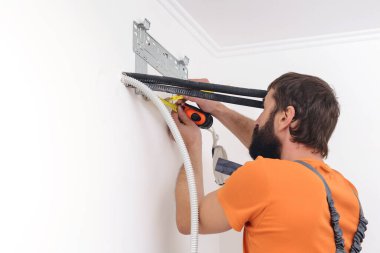 Adam yeni klima kurmaya hazırlanıyor. Kurulum sırasında modern klima. İşçi klimanın kapalı bir bölümünü kuruyor. Bakır tüpler ve plakalı radyatör.