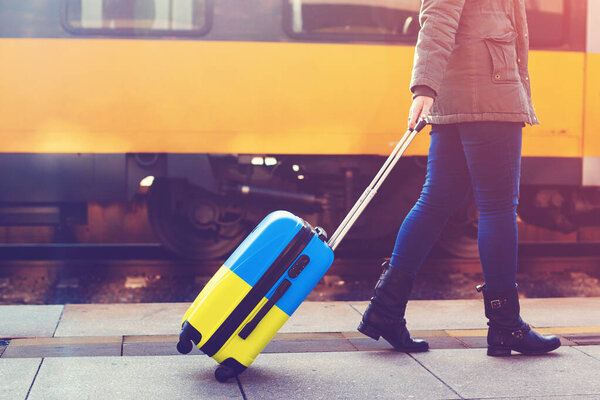 A refugee from Ukraine is fleeing Russian aggression against Ukraine. A suitcase in the color of the Ukrainian flag. Flight to Europe from the war.