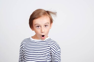 Stüdyoda poz veren şok olmuş bir çocuk. Çocuk stili ve moda. Duygularınla ve ifadenle yüzleş. Neşeli çocuk eğleniyor. Beyaz arka planda suratını buruşturan komik çocuk..