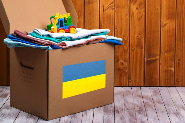 Donation box with Humanitarian aid with children\'s things and toys for Ukrainian refugees. Charity and Helping poor and needy people. Stay with Ukraine. Ukrainian flag on the box with donate.