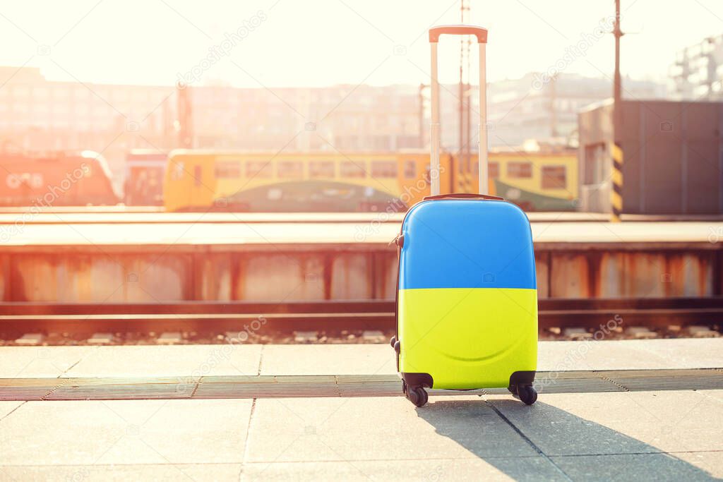 Suitcase of blue and yellow color oa railway. Stand with Ukraine. Ukrainian people leaving from the war. Ukrainian refugees concept.