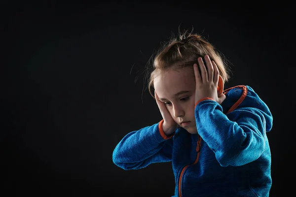 Unhappy sad boy over black background. Stress kid sitting alone in dark. Young boy suffering from psychological diseases, anxiety.