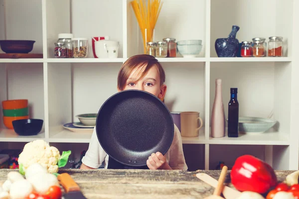 Boy at cooking classes. Child cooking. Cute little chef holding frying pan at kitchen. Funny boy wearing apron. Future profession. Chef trying a new recipe.