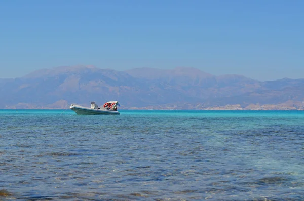 Girit adasının arka planına karşı deniz yüzeyindeki tekne